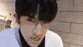 a close up of a young man 's face with a brick wall in the background .