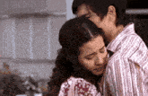 a man and a woman are hugging in a kitchen .