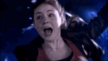 a woman is screaming in a dark room with her mouth wide open