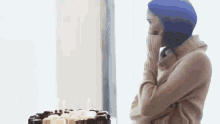 a woman in a sweater is standing in front of a birthday cake with candles .