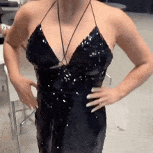 a woman is wearing a black sequined dress with her hands on her hips