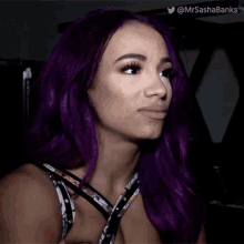a woman with purple hair is making a funny face and has the twitter handle @mrsashabanks
