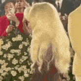 a woman with blonde hair is standing in front of a group of people .