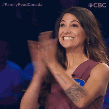 a woman in a purple dress is clapping her hands and smiling
