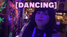 a woman is dancing in a dark room with neon lights