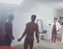 a man without a shirt is dancing in a room with two other people .