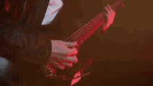 a man is playing an electric guitar in a dark room with red lights .