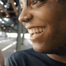 a close up of a person 's face with a nose ring and a smile .