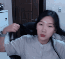 a woman in a white shirt is holding her hair in front of her face