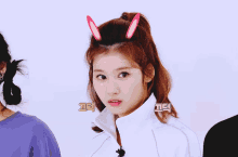 a girl with bunny ears on her head is making a silly face