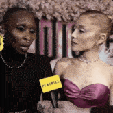 a woman in a pink dress is talking to another woman in a black dress .