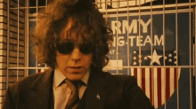 a man in a suit and tie stands in front of a sign that says army