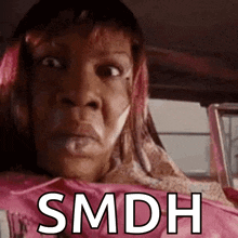 a woman with pink hair is sitting in a car with the words smdh written on the screen .