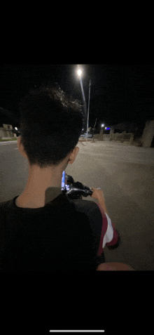 a person is riding a bike at night and looking at a cell phone
