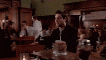 a man in a suit and tie is sitting at a table in a restaurant .