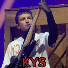 a man playing a guitar with the word kys in red letters