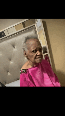a woman in a pink shirt is sitting in front of a bed .