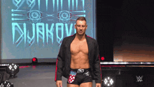 a shirtless wrestler is walking in front of a screen that says duakov