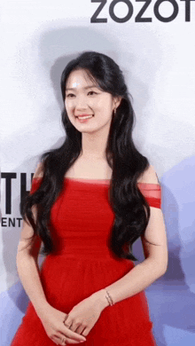 a woman in a red dress stands in front of a sign that says zozo