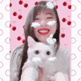 a woman holds a white cat with cherries on her face