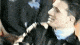 a man wearing a black jacket and tie is being held by a police officer .