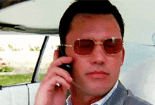 a man wearing sunglasses is talking on his cell phone