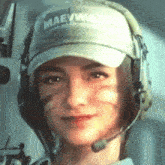 a woman wearing a maewwa hat and headphones smiles for the camera .