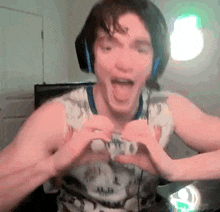 a man is wearing headphones and making a heart shape with his hands .