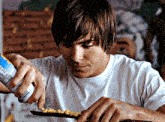 a man in a white shirt is pouring cereal from a can