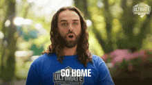a man with long hair and a beard wears a blue shirt that says go home ultimate challenge