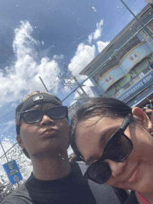 a man and a woman are posing for a photo in front of a building that says ba