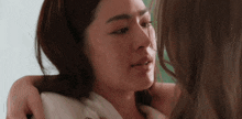two women are hugging and looking at each other