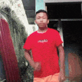 a young man in a red shirt and orange shorts is dancing in front of a door .