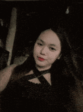 a woman with long hair is wearing a black top with a necklace around her neck