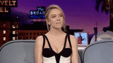 a woman sits on a couch in front of a sign that says the broad hollywood