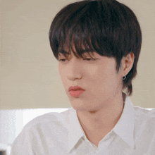 a close up of a young man wearing a white shirt making a funny face