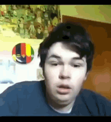 a young man is making a funny face in front of a cartoon wall .