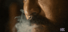 a man with a nose ring and a beard is smoking