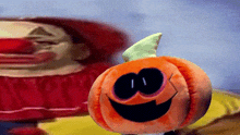 a stuffed pumpkin with a clown in the background is smiling