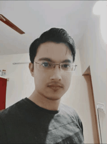 a man wearing glasses and a black shirt poses for a photo