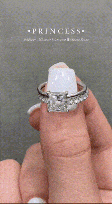 a woman is holding a wedding band and an engagement ring in her hand