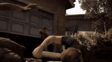 a man is laying on the ground in front of a garage door with another man standing behind him