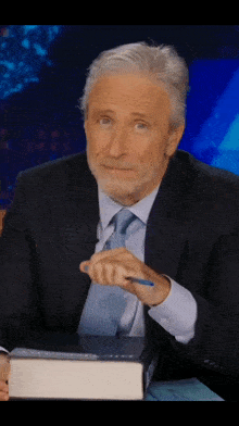a man in a suit and tie is holding a pen in his hand