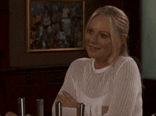 a woman in a white shirt is smiling in front of a picture