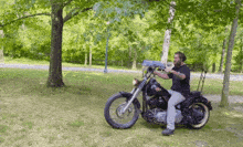 a man is sitting on a motorcycle in a park holding a gun