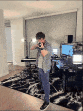 a man holding a gun in a room with a keyboard and a monitor