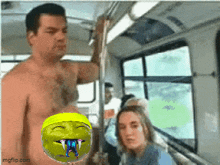 a man without a shirt is standing next to a shrek head on a bus