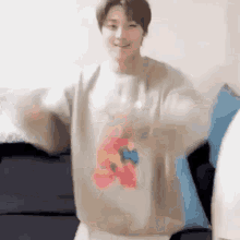 a man wearing a sweater with a bear on it is standing on a couch .
