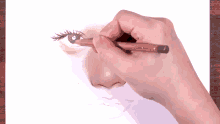 a person drawing a nose with a pencil on a piece of paper