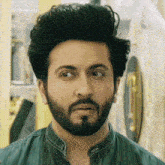 a man with a beard and a blue shirt is looking at the camera